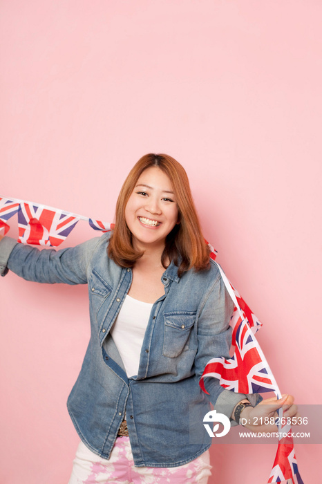 Young woman holding Union flag bunting, portrait