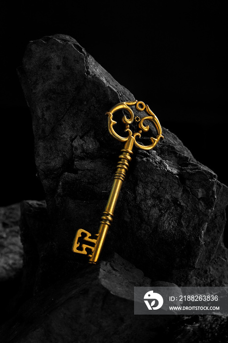 Antique Golden Key on Dark Coal Stone Surface Background