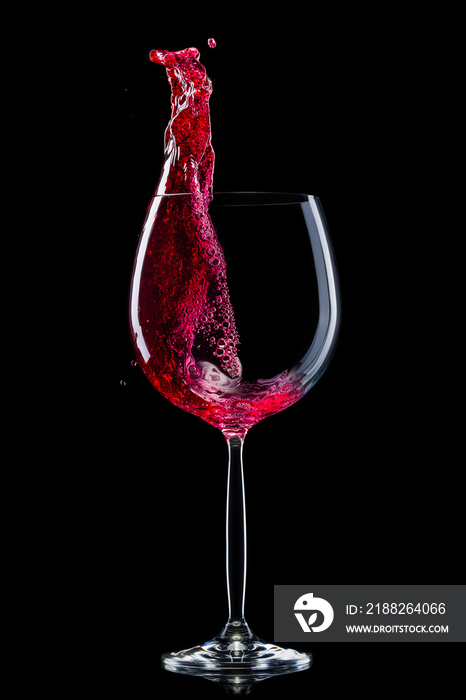 Glass for red wine with splashes isolated on black background.