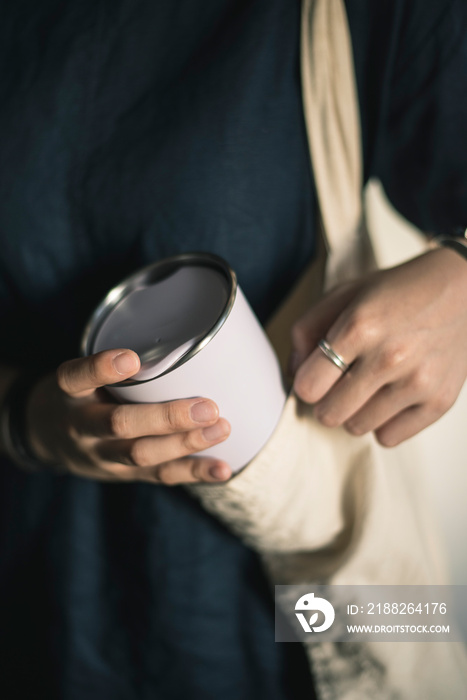 Young woman bringing and taking out tumbler, reusable coffee mug/cup from her bag.