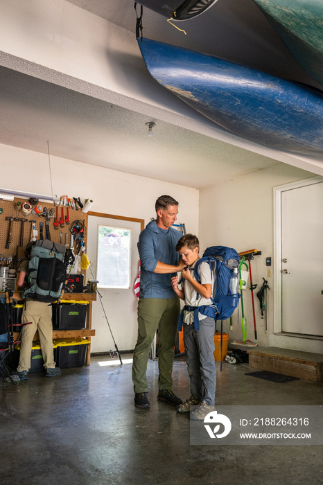 Air Force service member organizes gear with his sons before a backpacking trip.