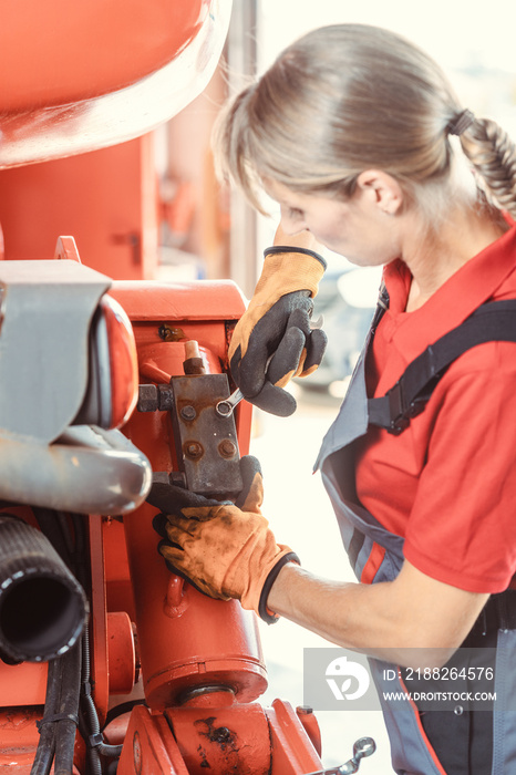 Woman machinist working with wrench of a farm machine