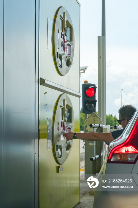 vertical view of a man taking ticket from a toll booth on a French highway