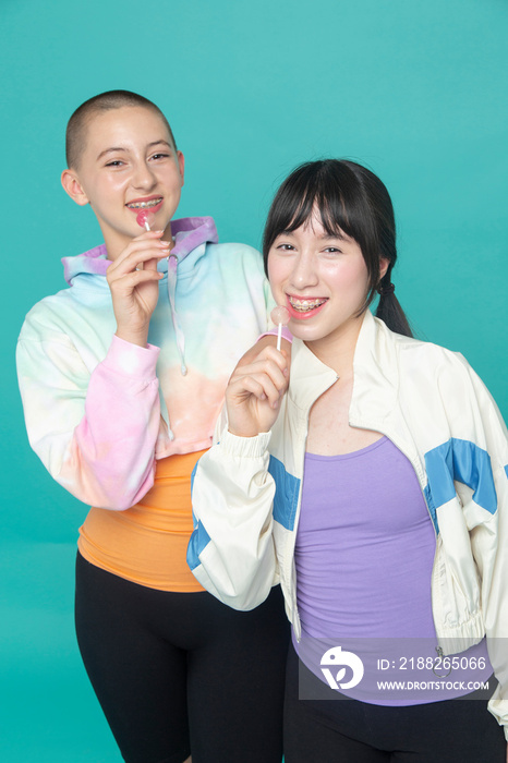 Studio portrait of two smiling girls with lollipops