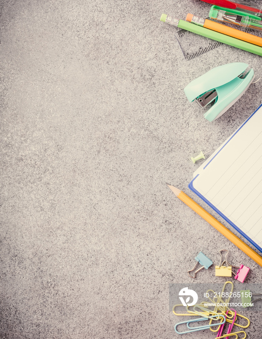 Assorted colorful school supplies on gray stone background. Concept with copy space. Retro style toned.