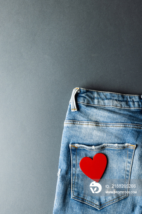 Vertical image of jeans with heart on grey background