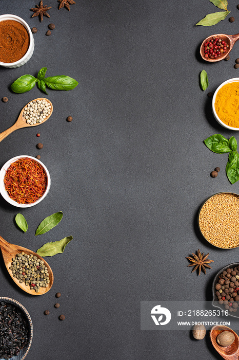 Assortment of aromatic herbs and spices on black rustic background with copy space for your design top view.