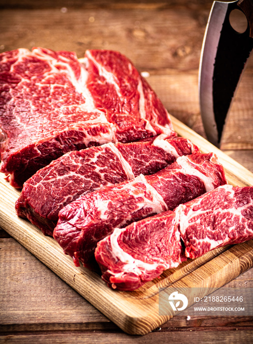 Raw beef on a cutting board with a knife.