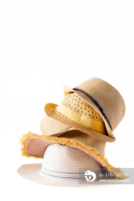 Vertical image of stack of straw hats on white surface