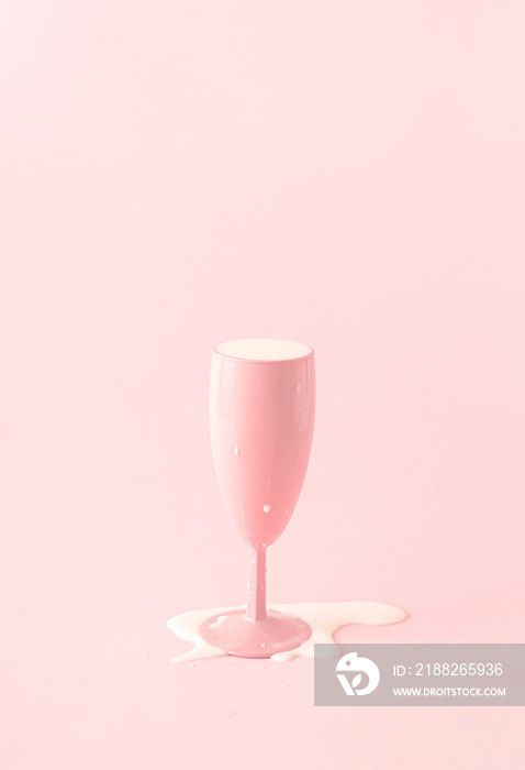 Pink champagne glass with spilled milk. Pink background.