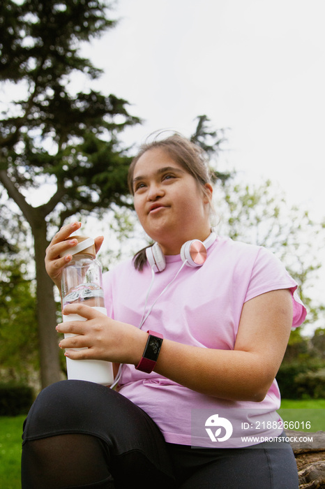 Young curvy girl with Down Syndrome holding reusable water bottle after workout