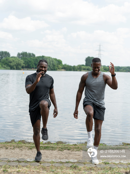 Two men exercising in park by lake