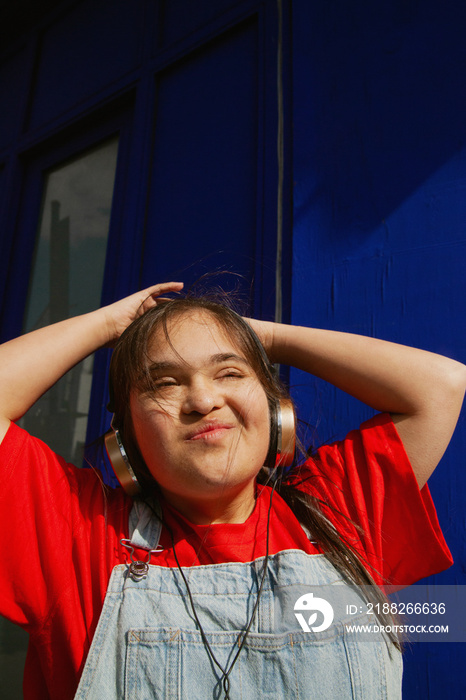 Young curvy woman with Down Syndrome dancing in the sun with headphones