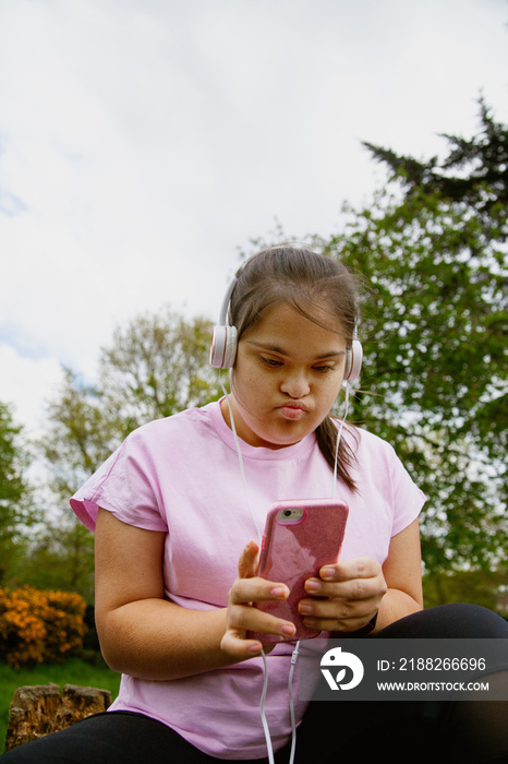 Young curvy girl with Down Syndrome relaxing and listening to music after workout