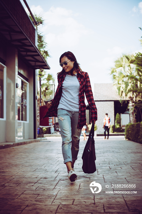 Portrait of young stylish hipster woman walking on urban street,