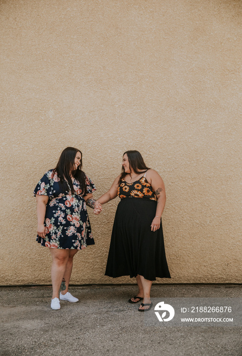 2 plus size women hold hands and talk