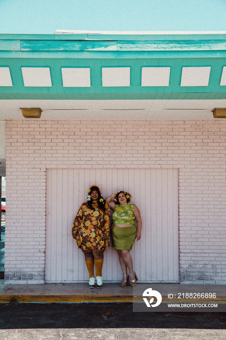 2 plus size women standing against a pink wall