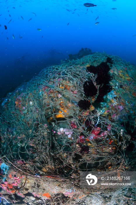 A huge discarded ghost fishing net entangled on a pinnacle on a tropical coral reef