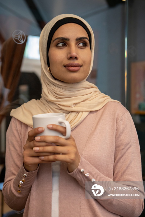 Portrait of smiling woman wearing headscarf holding cup