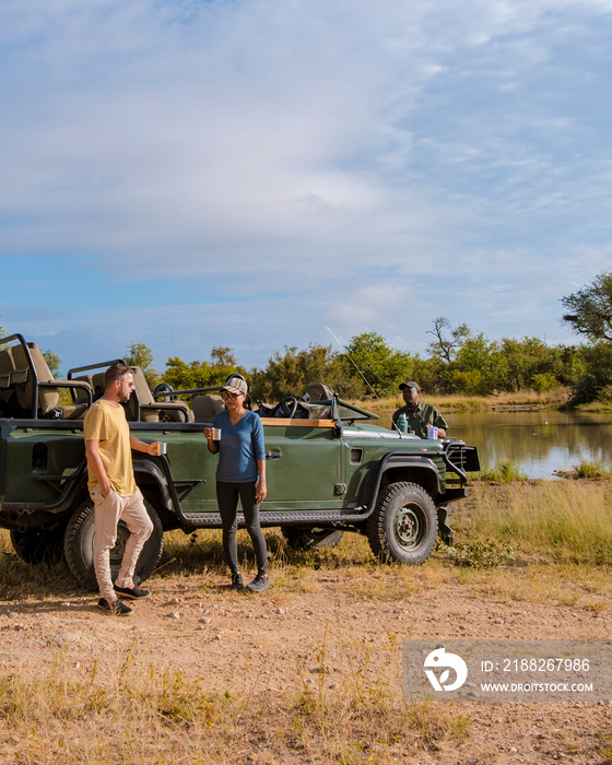 Asian women and European men on safari game drive in South Africa Kruger national park. a couple of men and women on safari drinking coffee in the morning