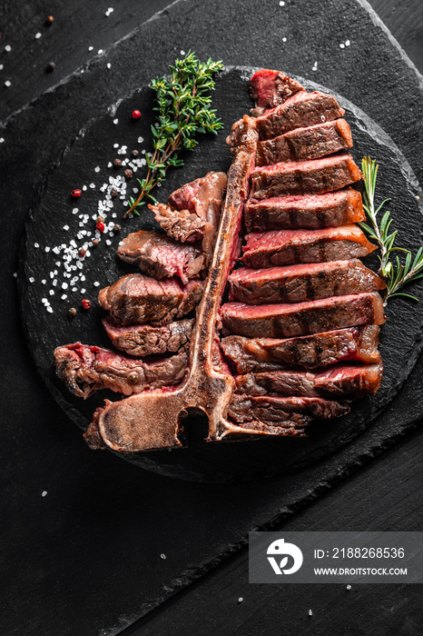 Piece of cooked T-bone or aged wagyu porterhouse grilled beef steak with spices served on on stone board. vertical image. place for text