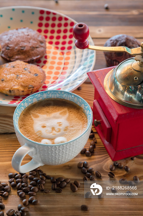 Red coffee mill, cup latte with a painted cat on milk foam and biscuits on a old wooden table.