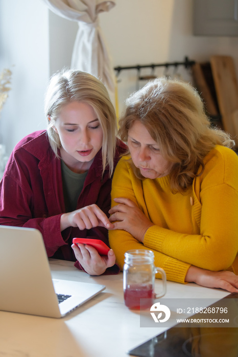 mother-in-law with a woman surfing Internet on laptop in kitchen of house