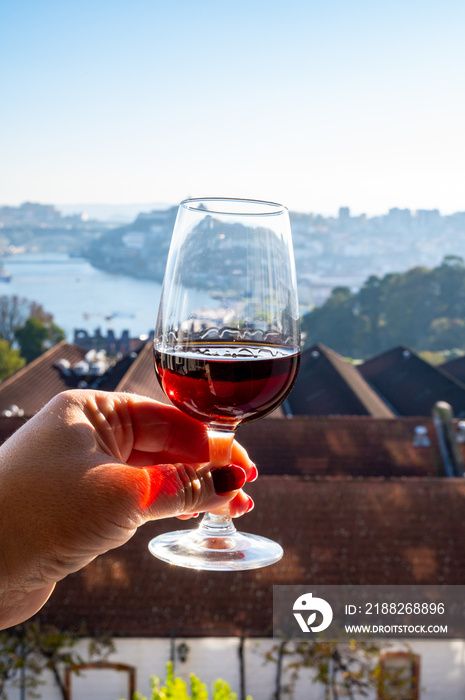 Tasting of different fortified dessert ruby, tawny port wines in glasses with view on Douro river, porto lodges of Vila Nova de Gaia and city of Porto, Portugal