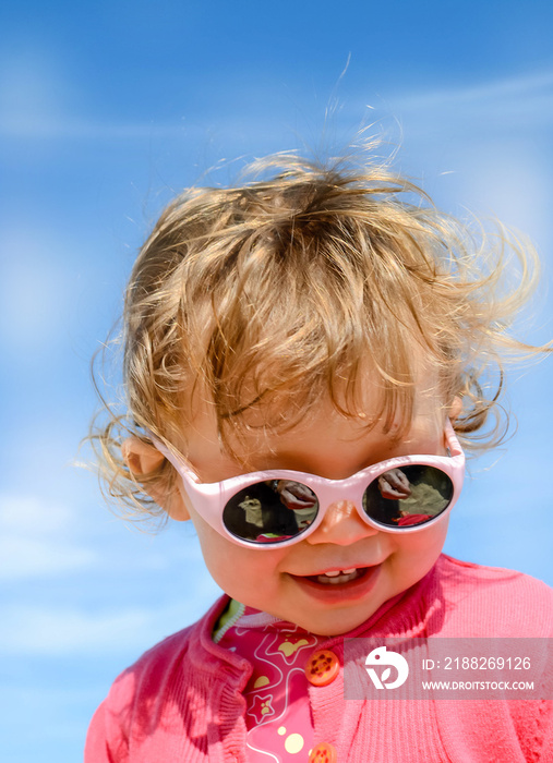 pretty little girl playing on the beach and protected from the sun