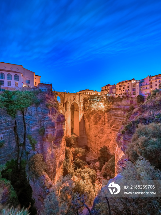 Puente Nuevo bridge and the houses built on the edge of the cliff at night, in the ancient city of Ronda, Spain.