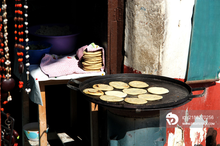 view of female indigenous hand making tortillas on comal, traditional food