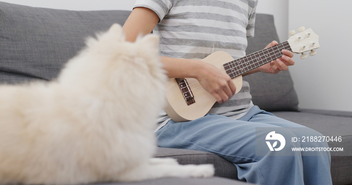 Pet owner play ukulele with her dog