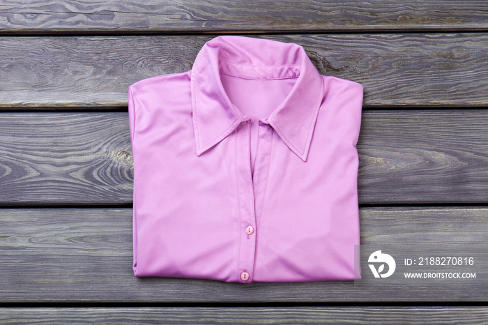 Folded pink silk shirt, flat lay. Grey wooden surface background.