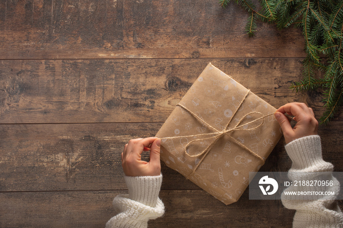 Christmas gift. Congratulations.Top view of woman holding traditional decorated gift box. Hands holding gift box on wooden background.