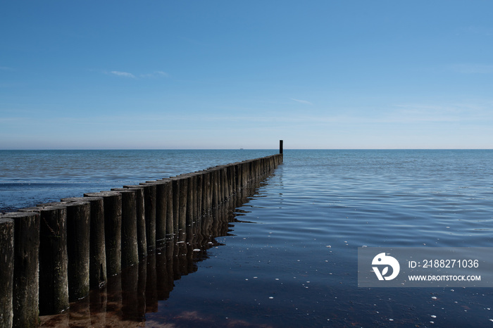 maritime background, wooden breakwater in calm baltic sea against blue sky