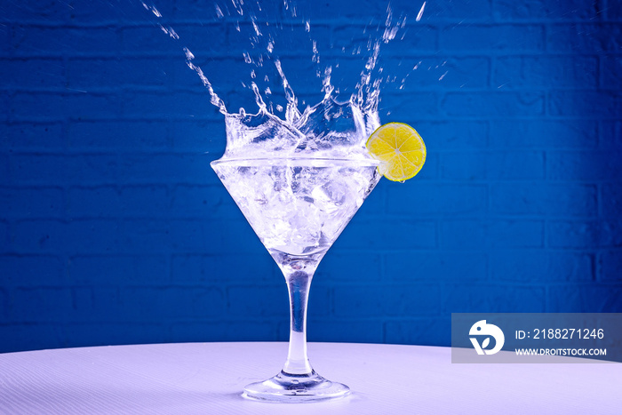 Vermouth in a martini glass and a slice of lime on a blue background, copy space.