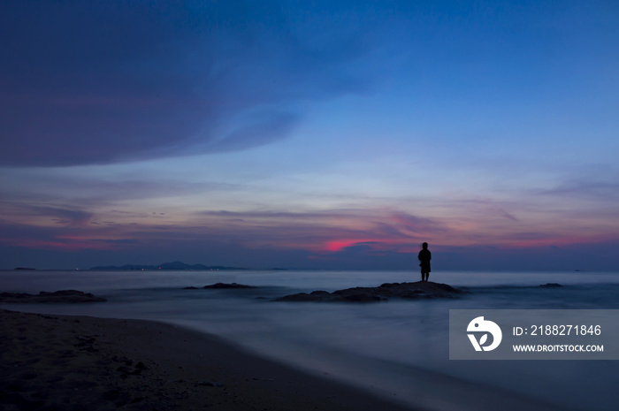 Colorful sky over sea and beach with man silhouette.