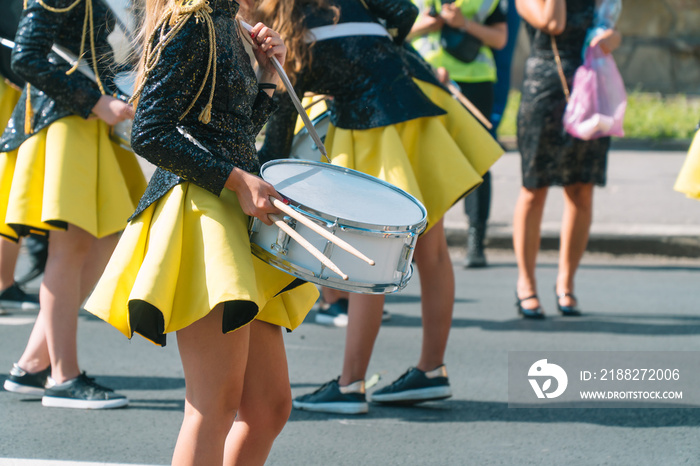 Street performance of festive march of drummers girls in yellow black costumes on city street. Street music concept