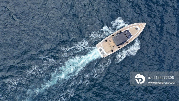 Aerial drone top down photo of small power boat with wooden deck cruising in deep blue Mediterranean sea