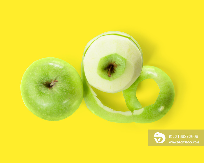 Two green apples with peeled skin isolated on yellow background. Top view