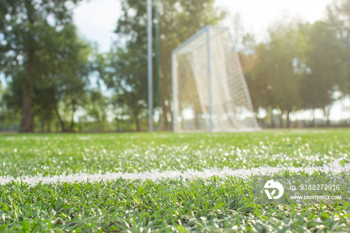 Defocused football goal on green grass early in the morning.