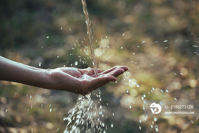 Water flow to hand in the garden on nature background.