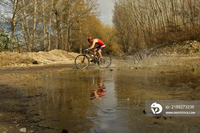 Cyclist crosses a stream with his bike and churns up the water.