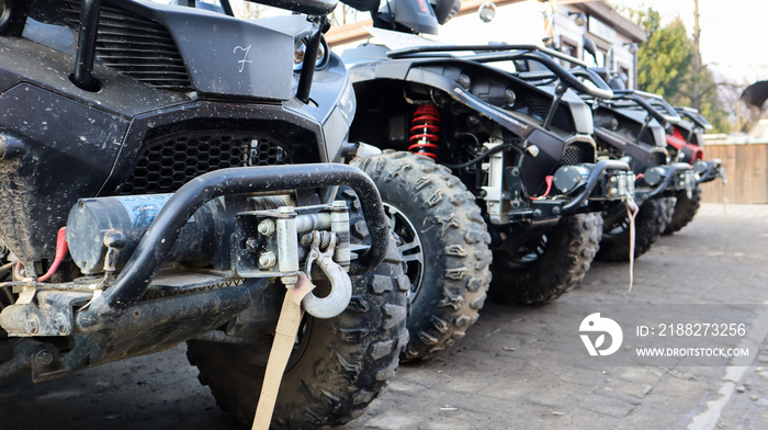 Many parked ATVs on a dirt road, close up. four-wheel car, all-terrain vehicle. large wheels with powerful legs. Mountain tour in the Carpathians