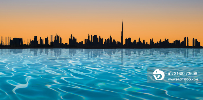 Dubai skyline. Panoramic view with infinity pool and silhouette of the city at sunset.