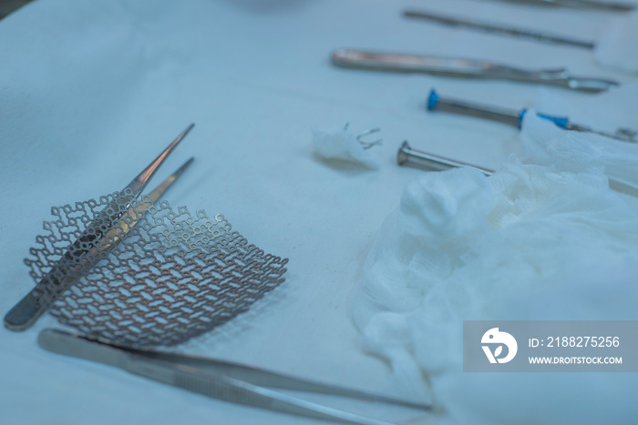 Close-up of a sterile operating table with medical neurosurgical instruments, including a titanium plate, a mesh for the skull, medical screwdrivers with screws.