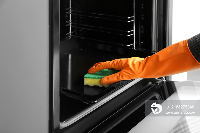 Housewife cleaning baking pan in oven