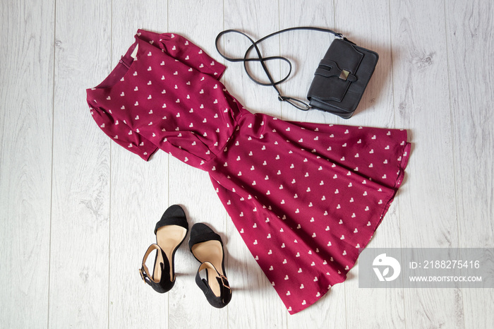 Sundress burgundy, black handbag and shoes on a wooden background. Fashionable concept