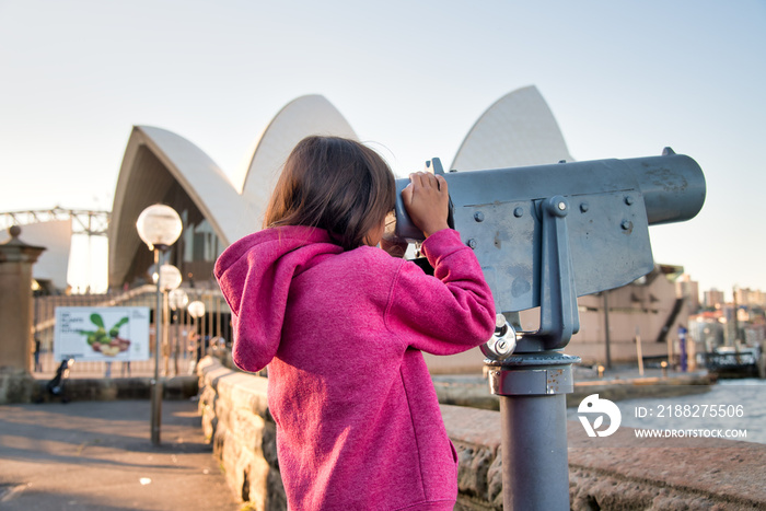 Happy smiling young girl visiting Sydney looking into a telescope