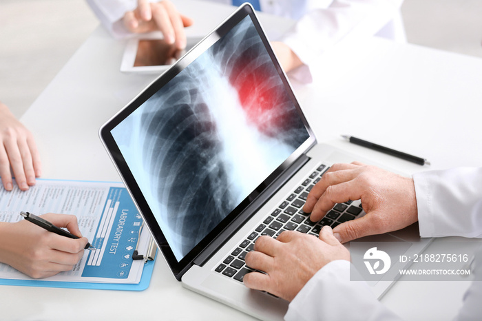 Asthma and health care concept. Doctors working at table, closeup. Chest x-ray scan on screen of laptop